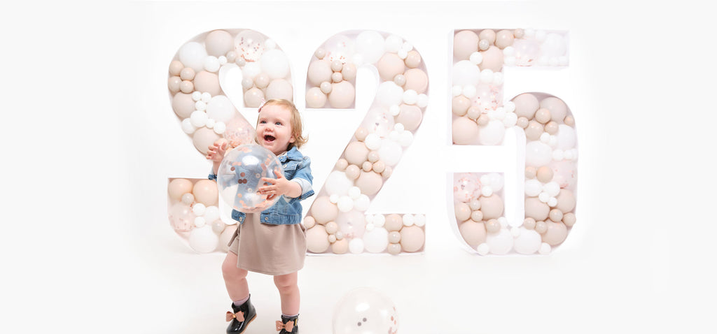 Toddler Stella with balloon and S-25 backdrop